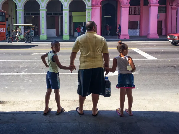 A boy walking in between yellow school buses